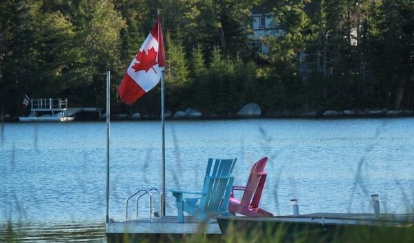 Canadian flag on jetty with adirondack chairs in lake