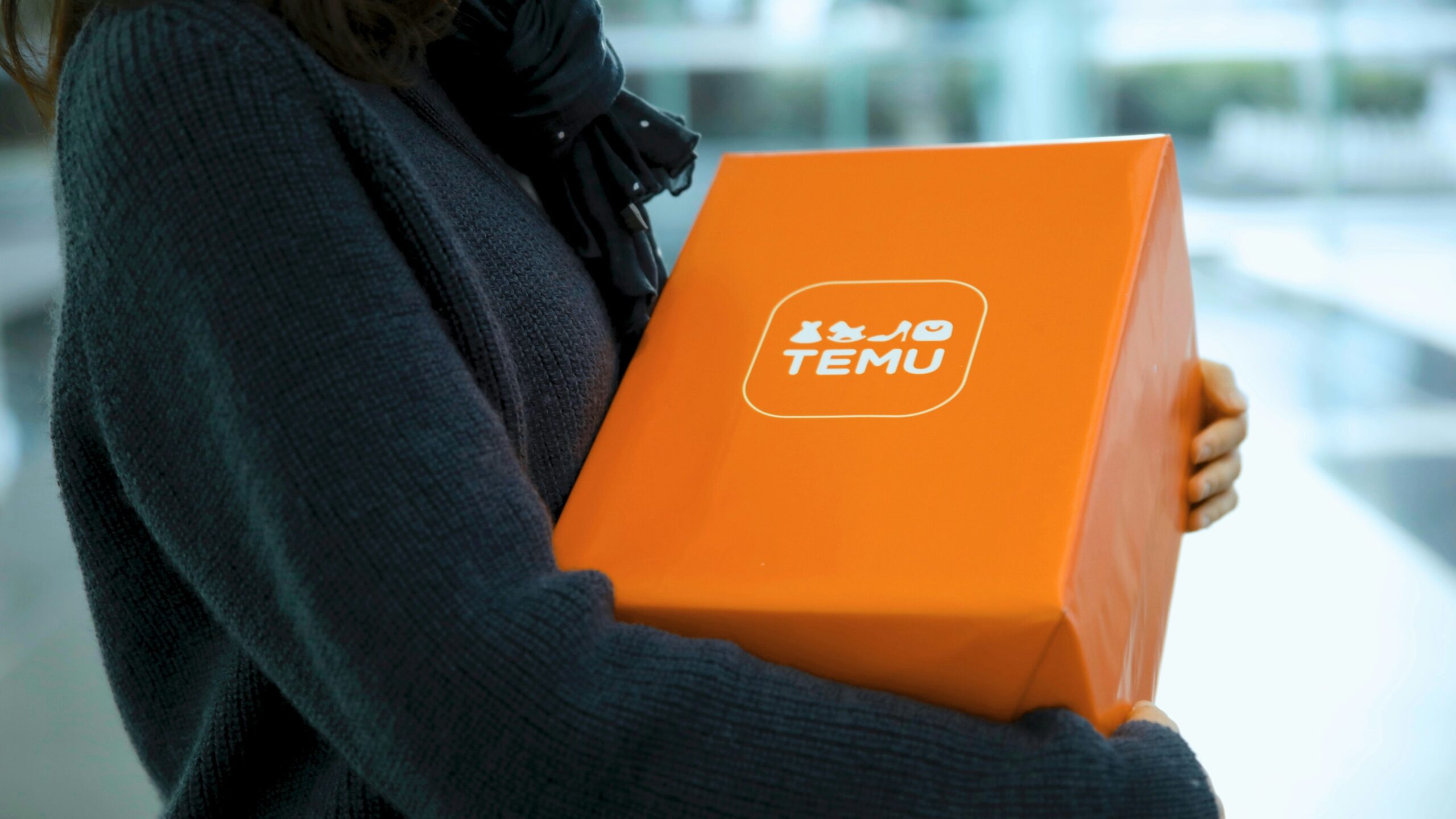 Woman holding an orange temu package