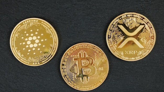 Gold cryptocurrency coins Bitcoin Cardano and Ripple on a dark background