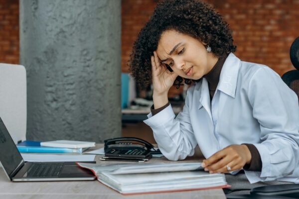 Businesswoman experiencing fatigue while working on financial paperwork at her desk.