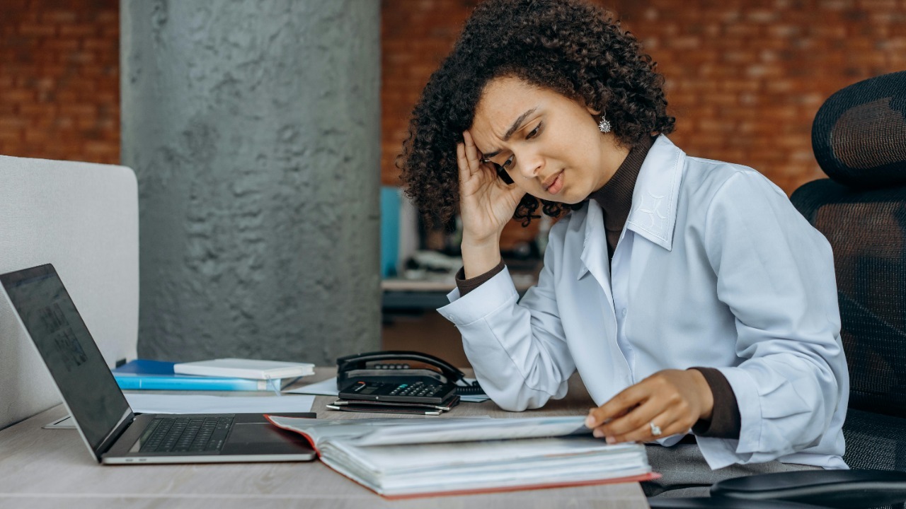 Businesswoman experiencing fatigue while working on financial paperwork at her desk.
