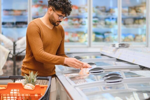 Arab customer choosing frozen food in supermarket refrigerator