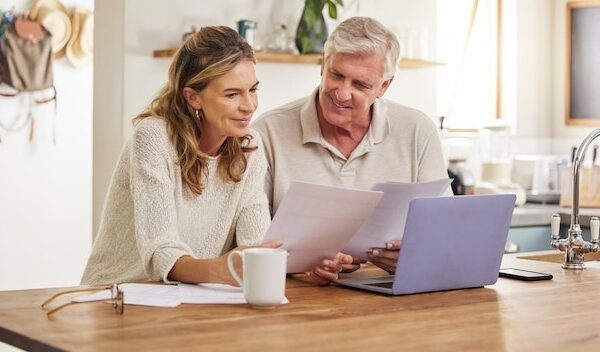 Retirement finance and couple with budget on laptop satisfied with home expenses in New Zealand Happy positive and married senior people checking financial documents for investment payment