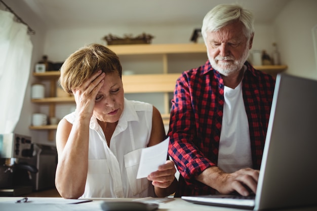 Senior couple paying bills online on laptop