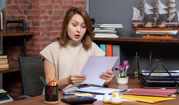 Front view of wondered woman checking papers sitting at office