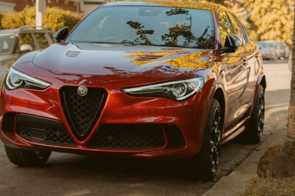 A red alfa romeo suv is parked on the street.