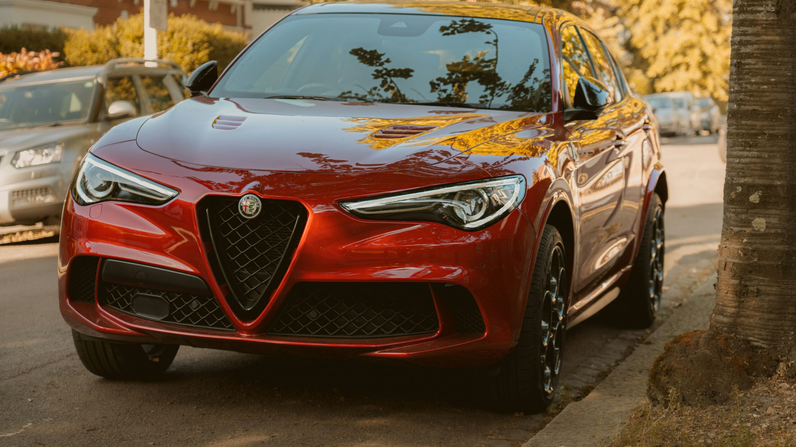 A red alfa romeo suv is parked on the street.