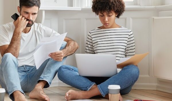 Photo of two mixed race coworkers read documentation, concentrated on solving problem with planning