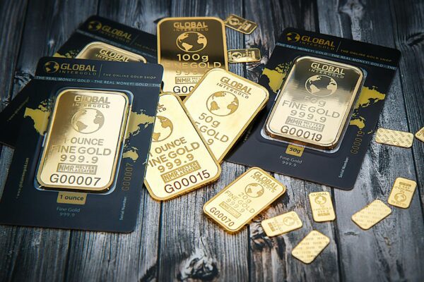 A collection of fine gold bars displayed on a textured wooden surface.