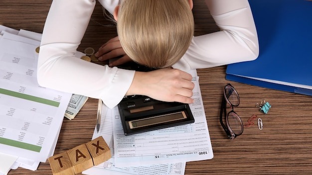 Tired businesswoman of calculating expenses at desk in office