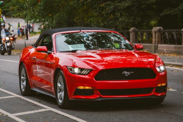 A red convertible mustang is driving down the street.