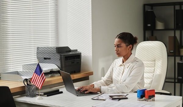 Visa center employee concentrating on her online work on laptop she typing data of documents