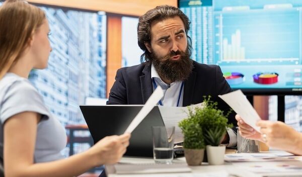 Financial advisor in office meeting with clients guiding them in trading shares