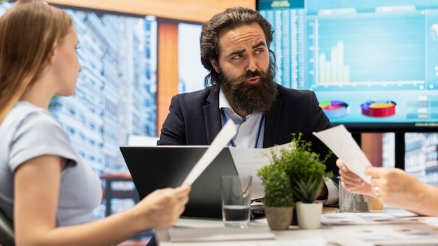 Financial advisor in office meeting with clients guiding them in trading shares