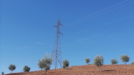 Low angle view of electricity pylon on field against clear blue sky