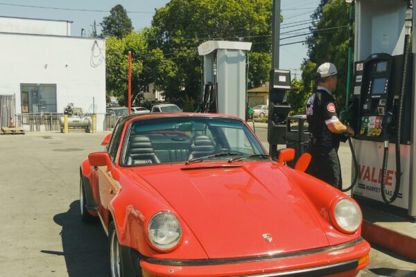 a red car parked next to a gas pump