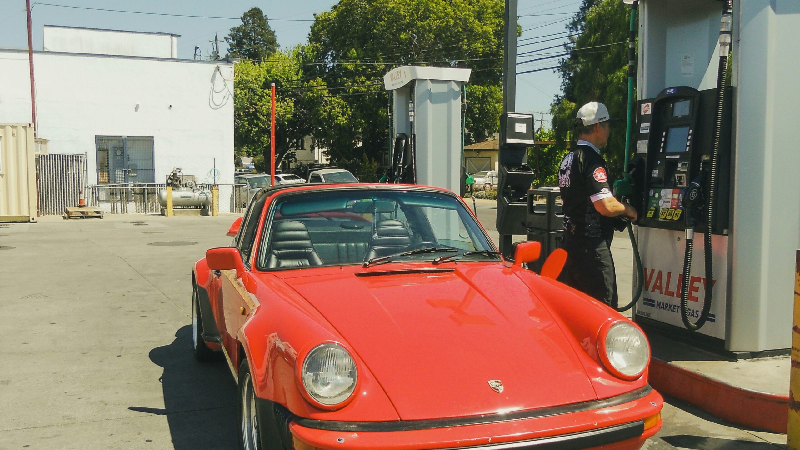 a red car parked next to a gas pump