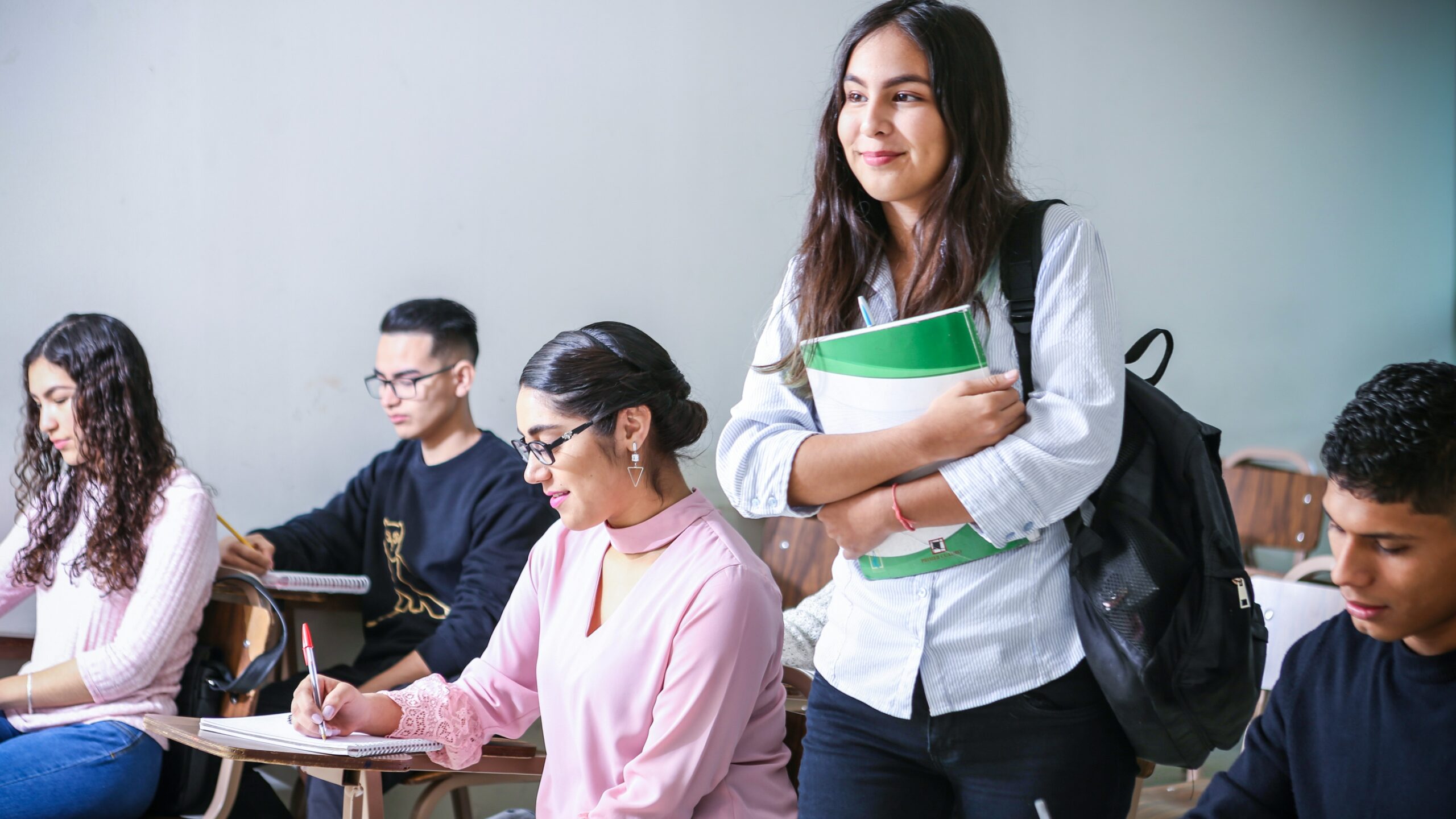 woman carrying white and green textbook