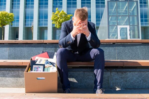 Stress and jobless concept, former employee sitting with his belongings stuffed in a box next to him