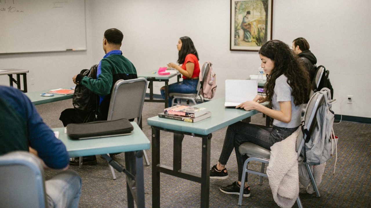 Students engaged in study inside a college classroom with books and discussions.