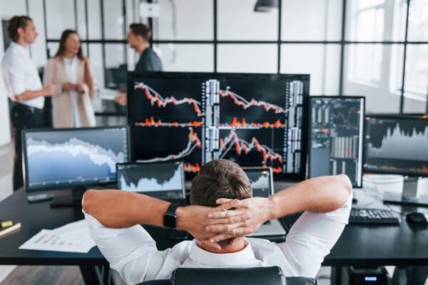 Man sits on chair and takes break Team of stockbrokers works in modern office with many display screens