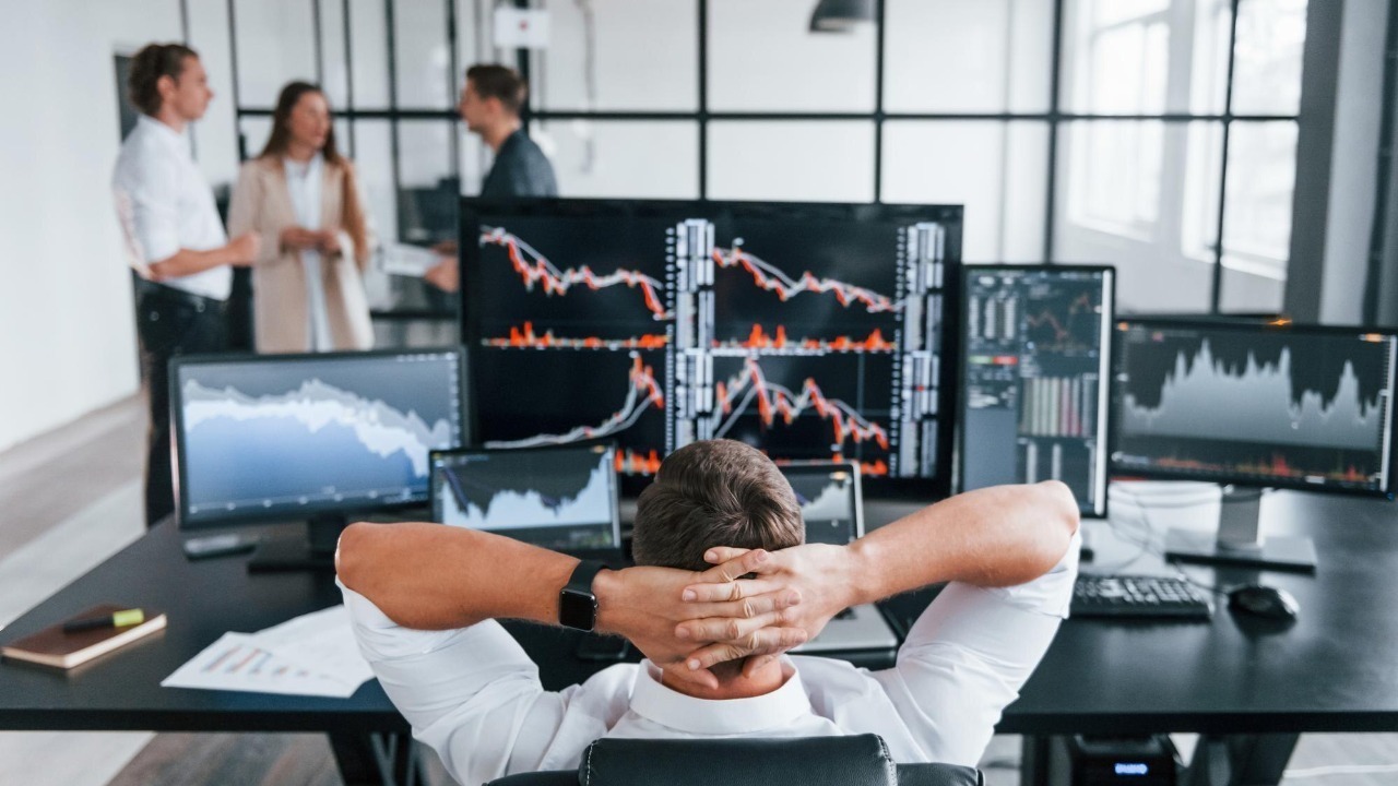 Man sits on chair and takes break Team of stockbrokers works in modern office with many display screens