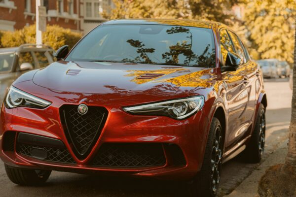 A red alfa romeo suv is parked on the street.