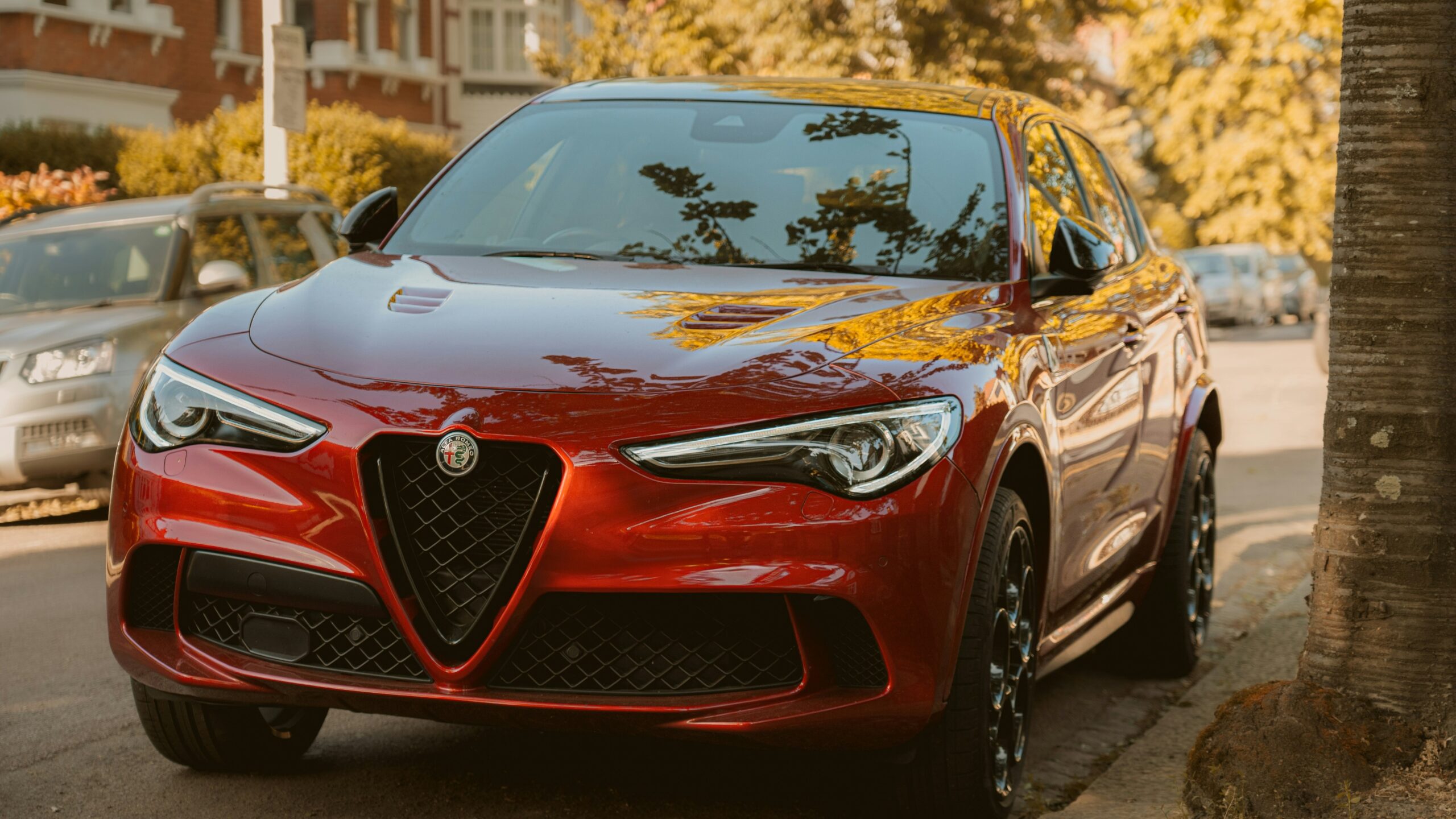 A red alfa romeo suv is parked on the street.
