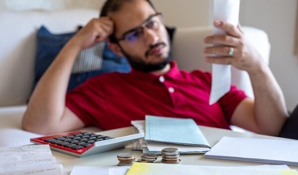 Man is frustrated from his living bills and calculating them in front of his couch in living room