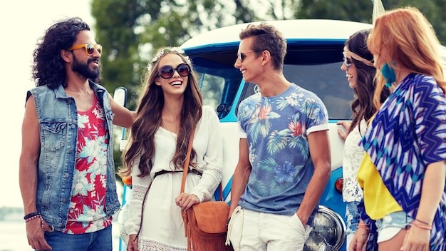 summer holidays, road trip, vacation, travel and people concept - smiling young hippie friends over minivan car