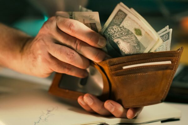 Hands holding us dollar bills in a brown leather wallet