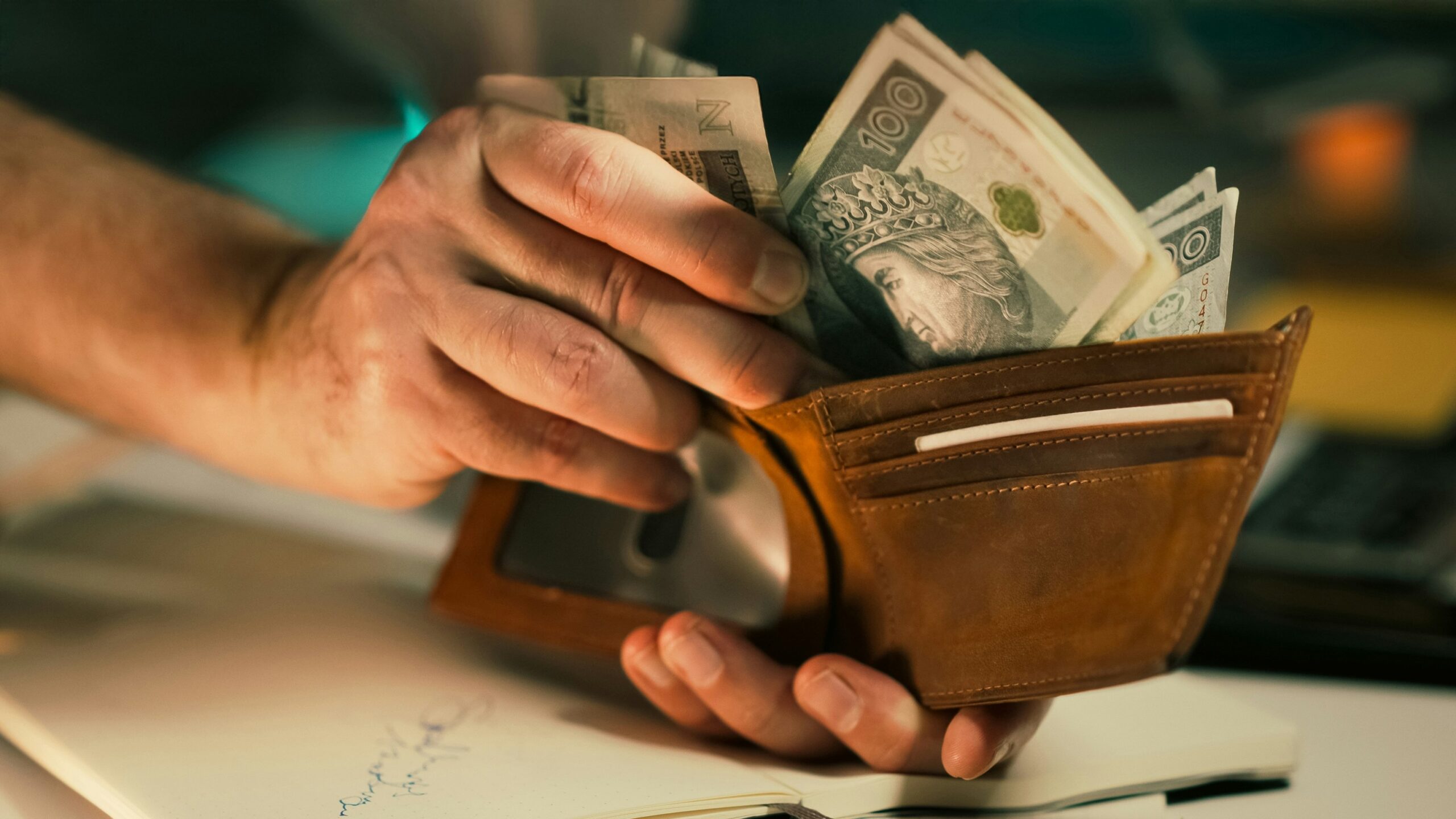 Hands holding us dollar bills in a brown leather wallet