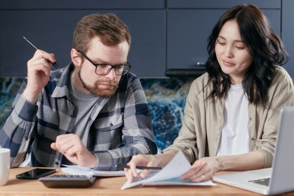 A couple is reviewing and calculating their household bills together at home.