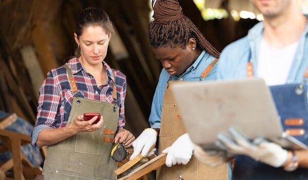 Portrait of carpenter male worker standing with laptop in workshop