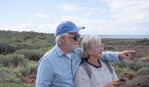 Carefree senior couple in walking day in countryside looking at footpath map enjoying trekking day