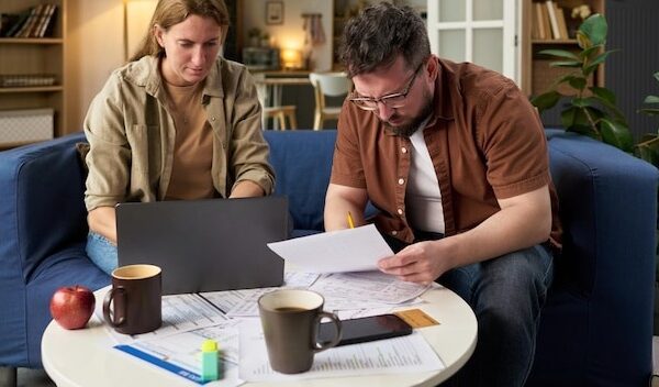 Caucasian young adult man and woman reviewing financial papers while paying taxes