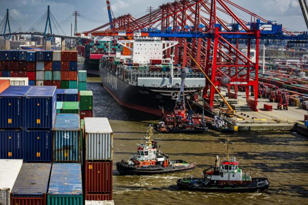 a tug boat in the water next to a large cargo ship