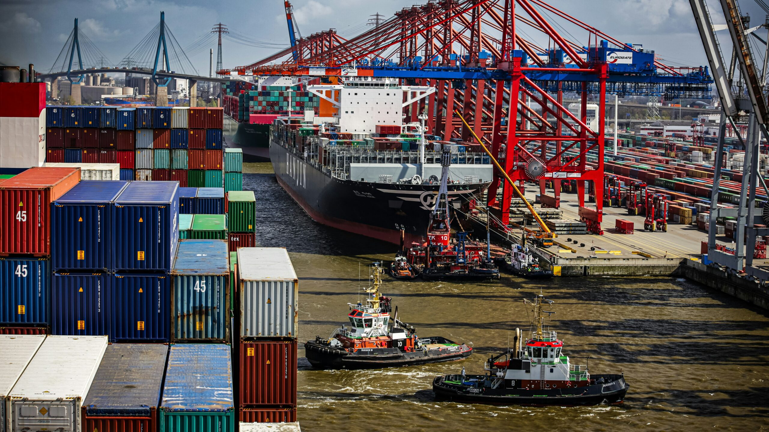 a tug boat in the water next to a large cargo ship