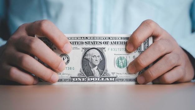 Businessman holding USD dollar banknote with stock market trading graph for Dollar currency is the main exchange and transfer money in the world
