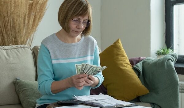 Senior mature woman using calculator holding paper bill calculating money budget tax