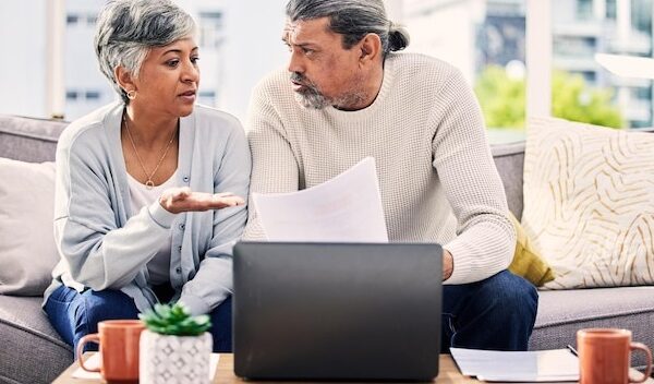 Senior couple documents and stress on laptop with financial paperwork taxes or retirement questions at home Planning debt and elderly people on sofa for life insurance bills or asset management