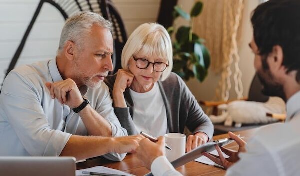 Financial advisor explaining paperwork to elderly retired couple front of desk