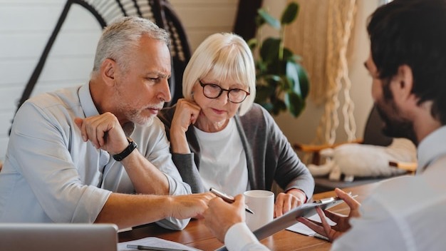 Financial advisor explaining paperwork to elderly retired couple front of desk