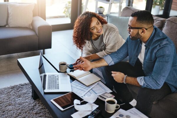 Home couple and documents for finances laptop and planning for savings increase and wealth distribution Apartment man and woman on couch pc and investment portfolio with paperwork for taxes