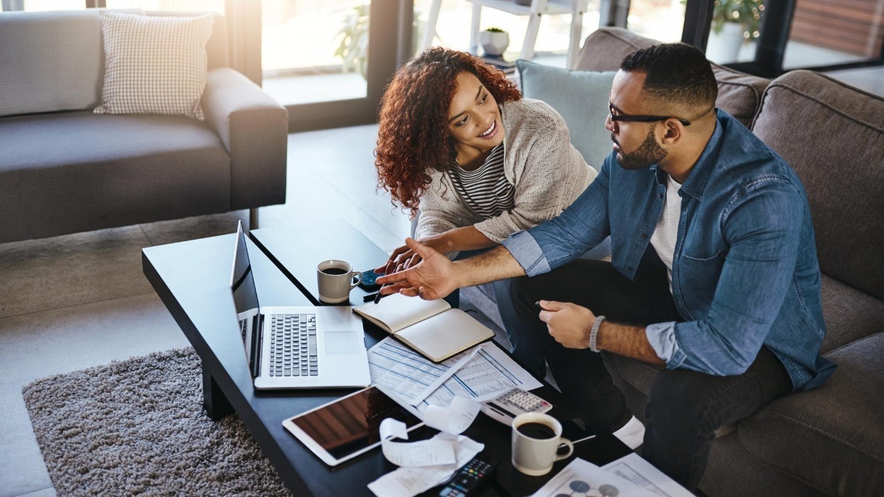 Home couple and documents for finances laptop and planning for savings increase and wealth distribution Apartment man and woman on couch pc and investment portfolio with paperwork for taxes