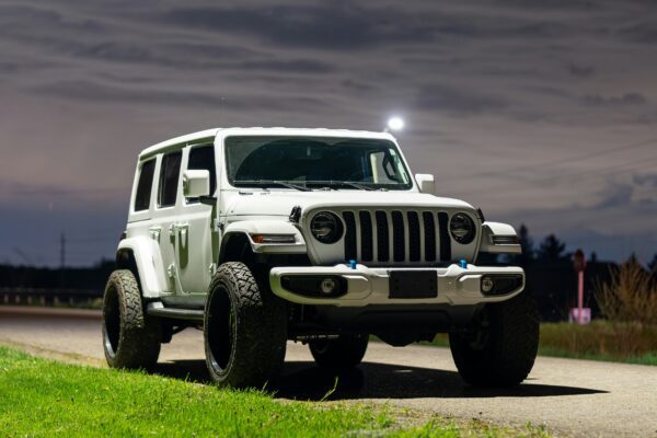 a white jeep driving down a road at night