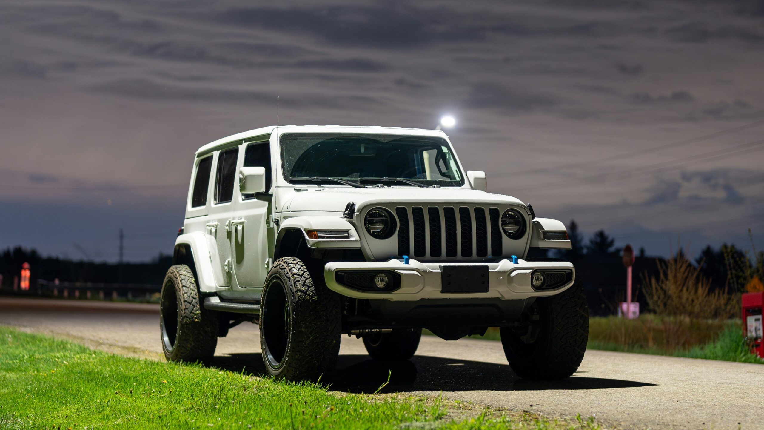 a white jeep driving down a road at night