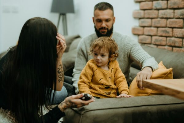 a man sitting on a couch next to a little girl
