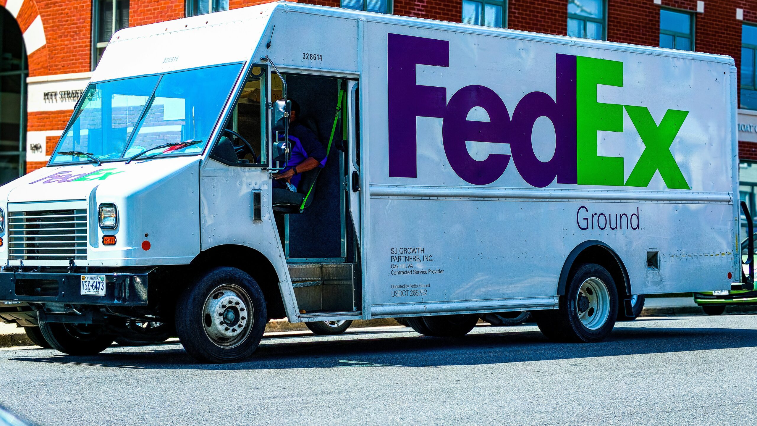 man in green jacket standing beside white and blue van during daytime