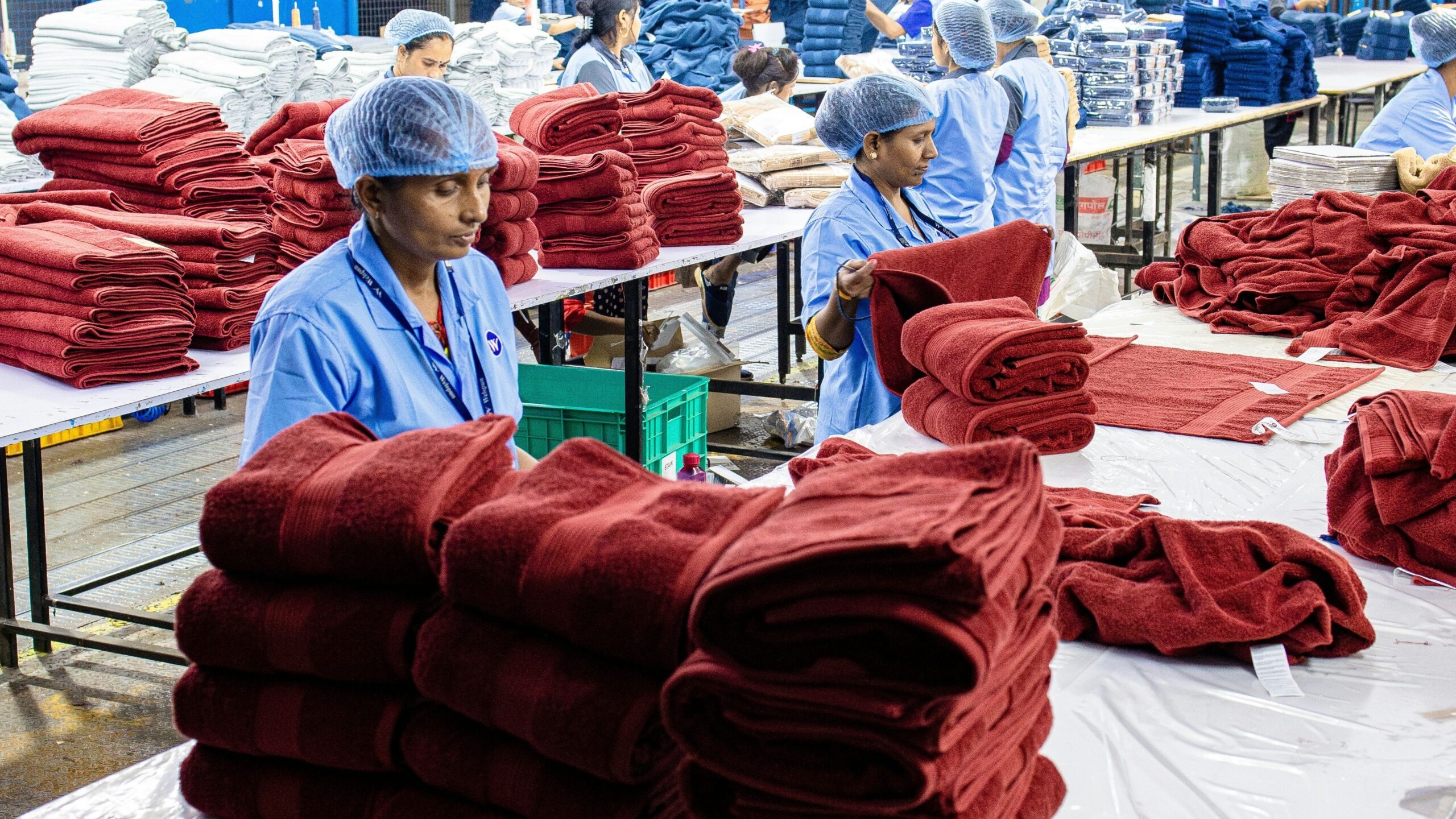 Workers fold and stack textiles in a factory.